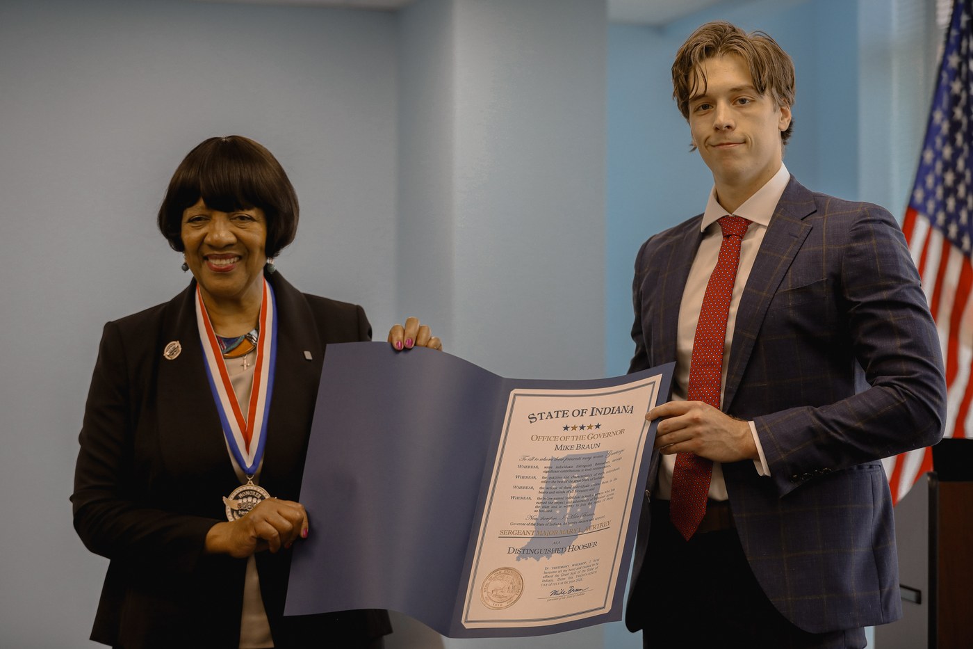 Jett Brownlee of the Office of Governor Mike Braun presents Mary L. Aurtrey a proclamation